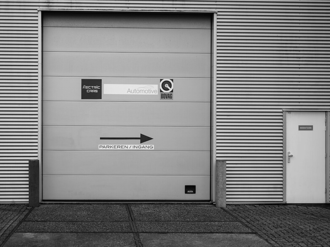 Clean modern car parked in front of a workshop entrance